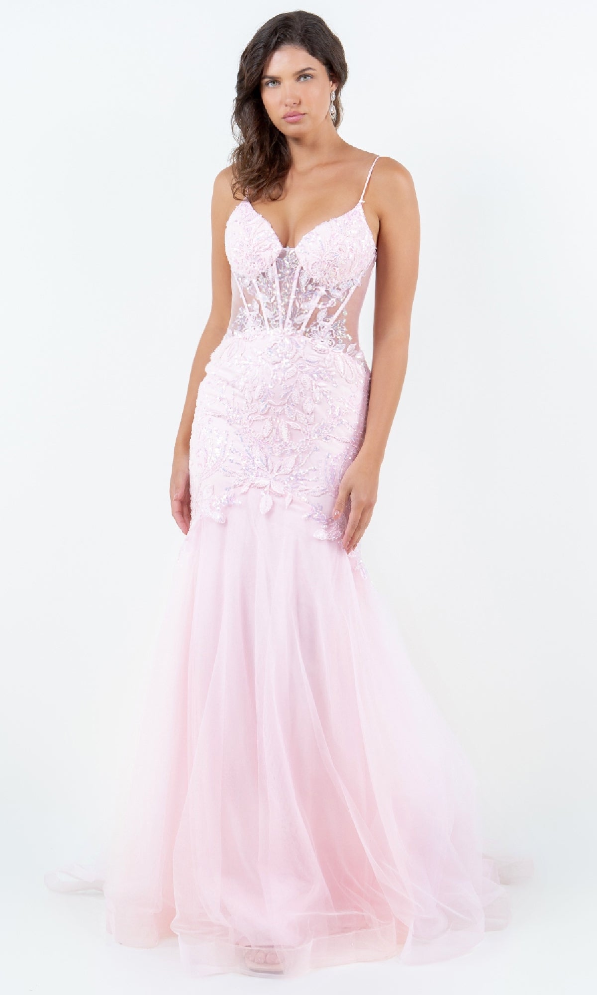 A woman stands against a plain white background wearing the Cinderella Couture 8276J, a light pink, fitted mermaid prom dress with a sheer lace bodice, thin straps, and flared tulle skirt.